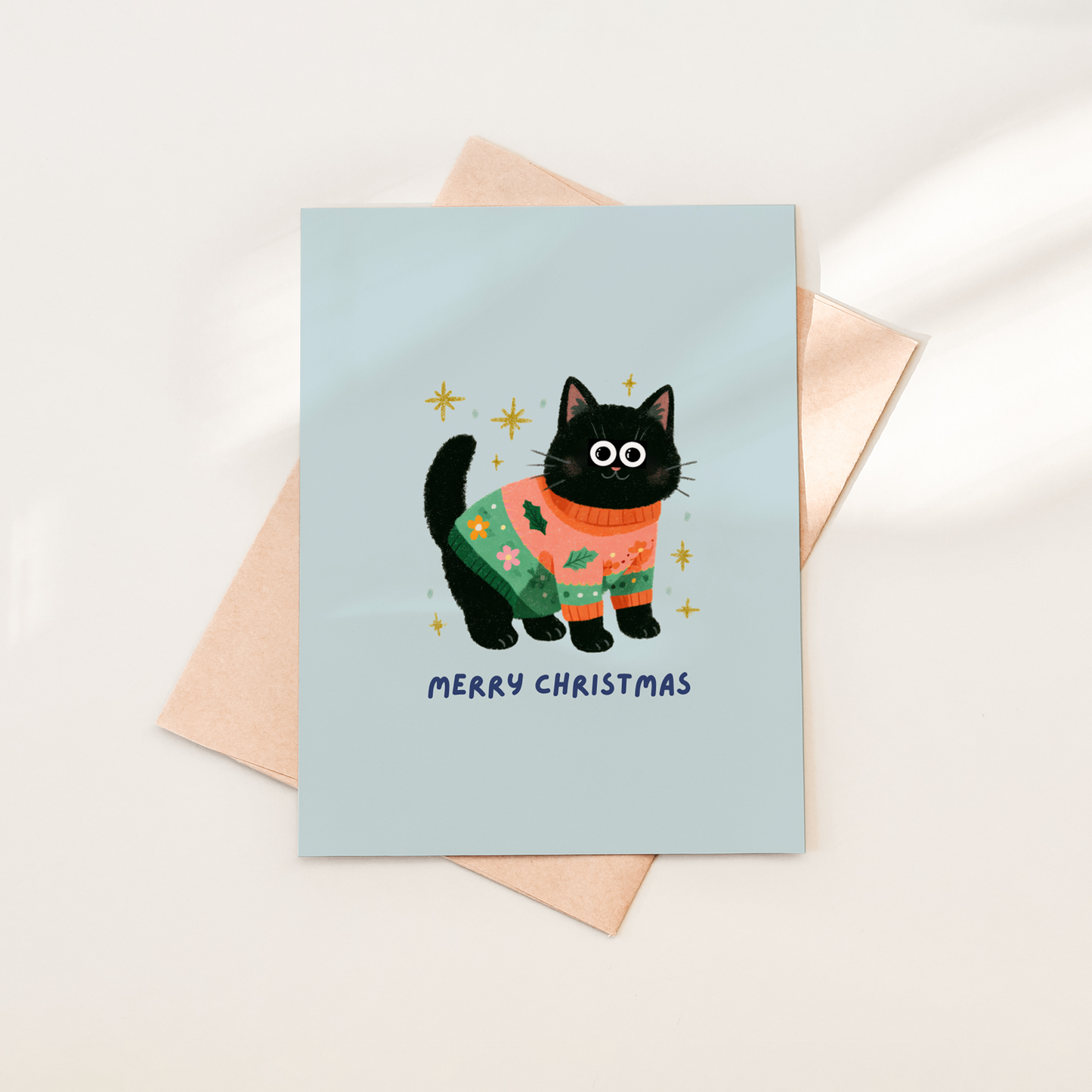 Greeting card with a black cat in a Christmas sweater on a light blue background