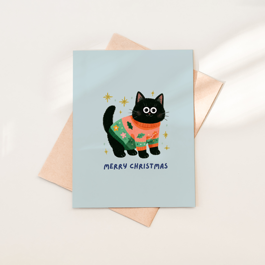 Greeting card with a black cat in a Christmas sweater on a light blue background